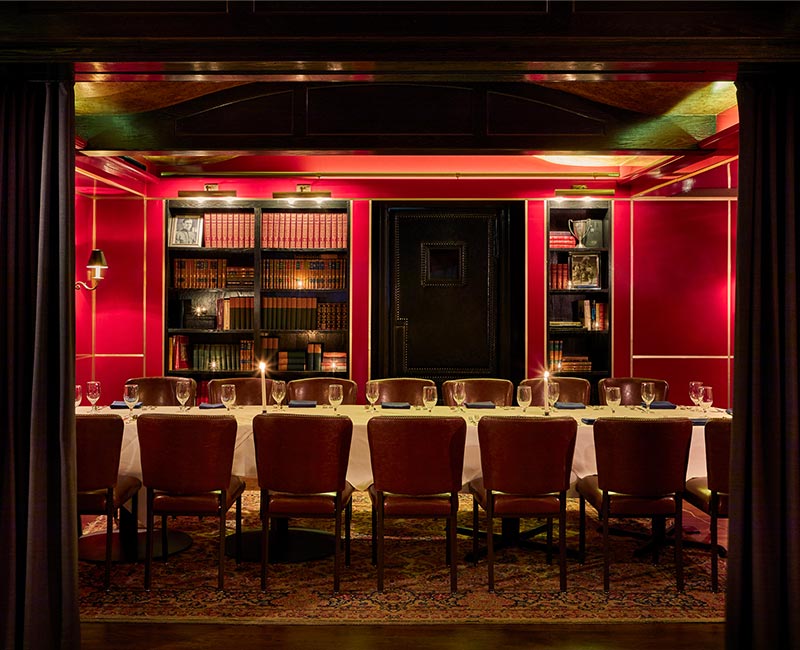 The Red Room is set with a long table and chairs for a private dining event